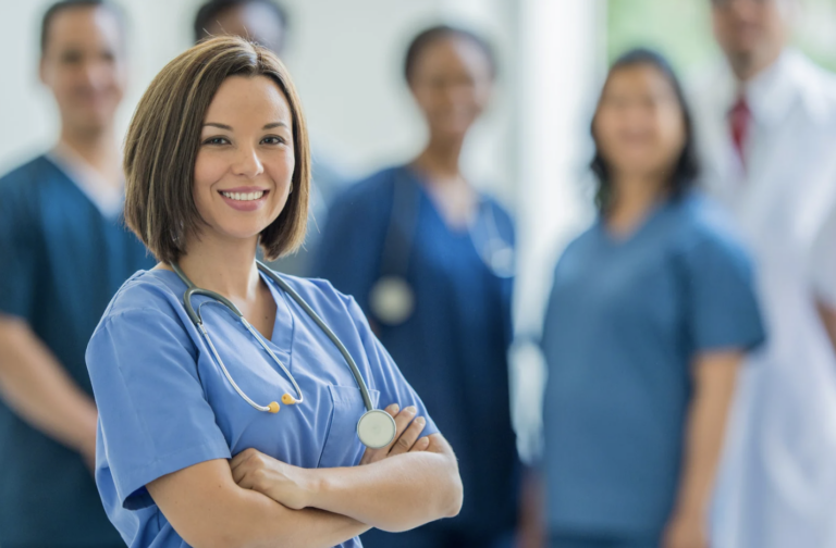 A woman standing with arms crossed and a stethoscope around her neck.